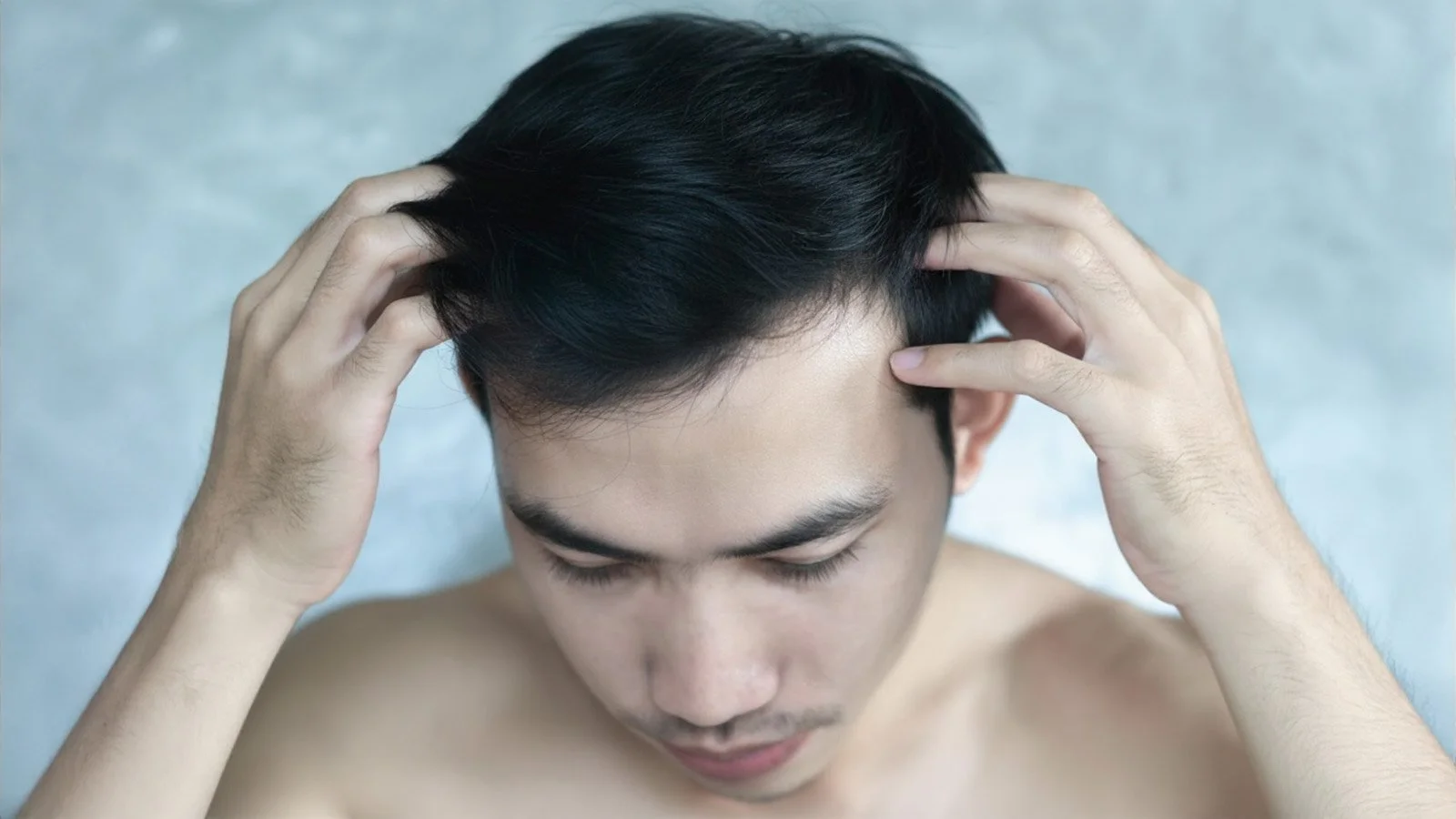Close-up portrait of shirtless man checking his hair